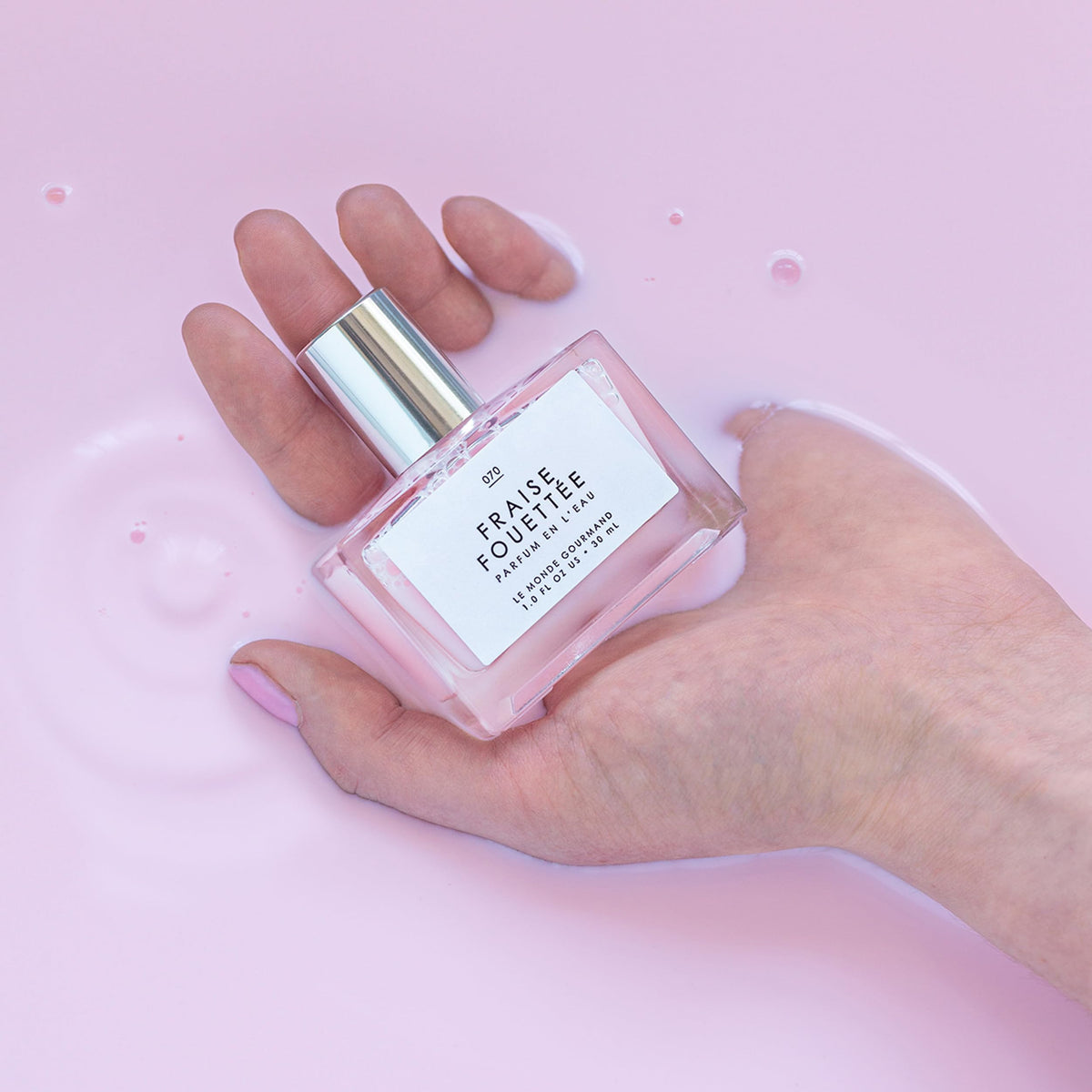 Bottle of Le Monde Gourmand Fraise Fouettée Eau de Parfum with strawberries