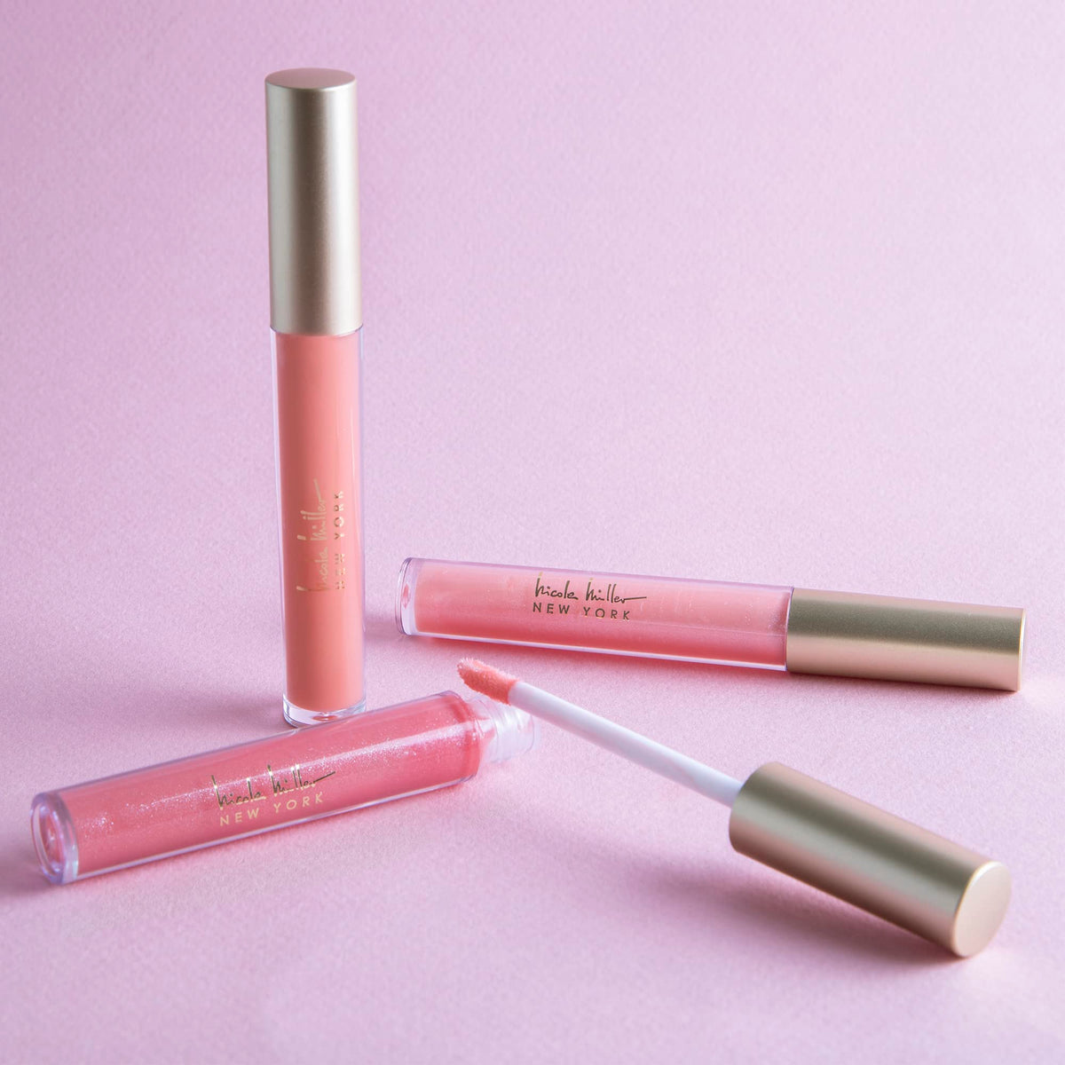 Close-up of Nicole Miller lip gloss tubes showing shimmery finishes