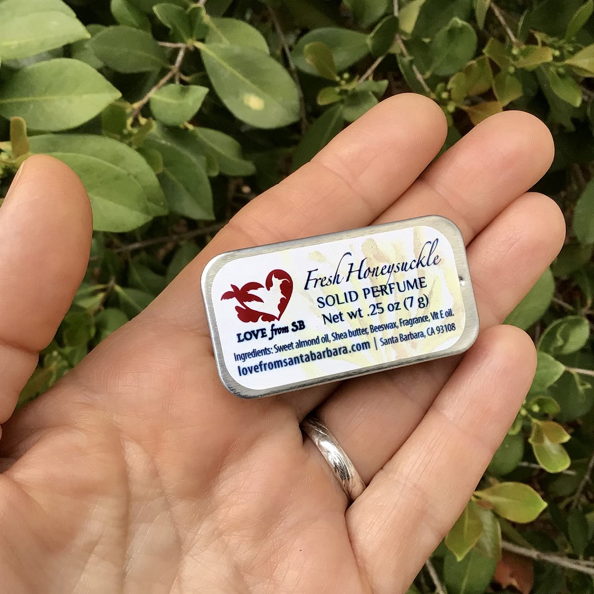 Compact Honeysuckle Solid Perfume beside a purse