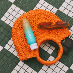 COOLA Clear Sunscreen Spray SPF 30 on a beach towel