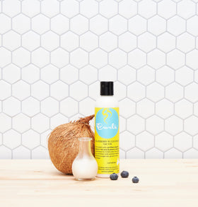 Curls Blueberry Bliss Hair Milk with a background of blueberries and coconuts
