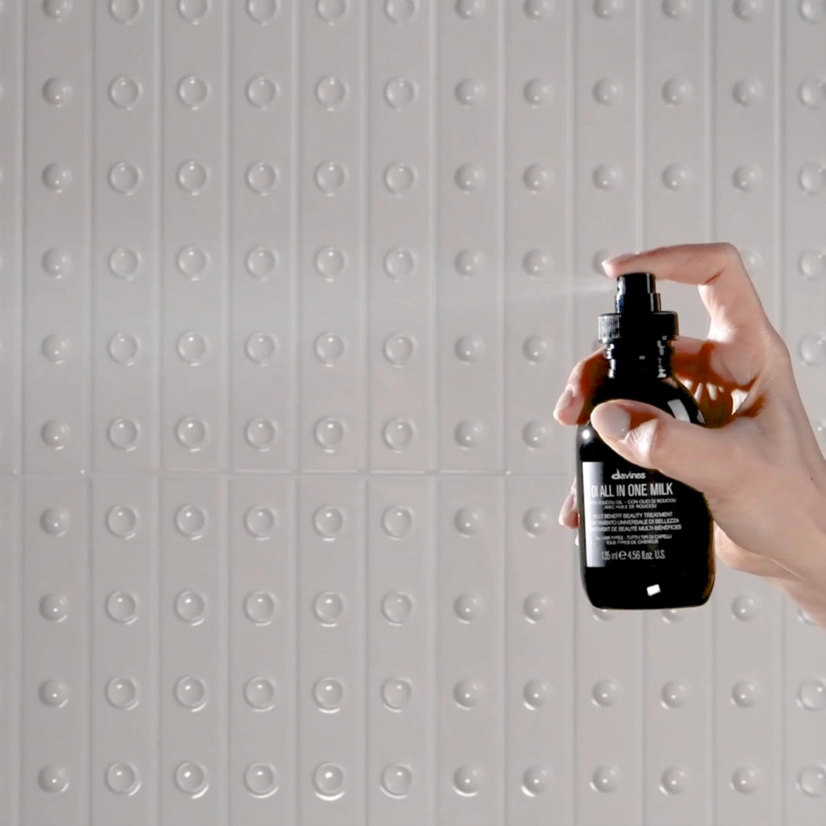Davines OI Shampoo pouring out of the bottle