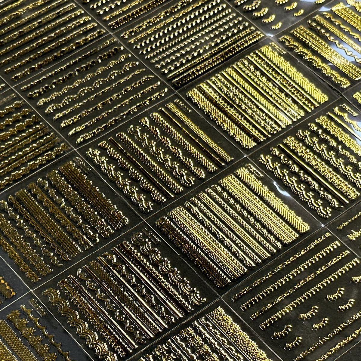 Different styles of SPLOCUDU gold nail stickers laid out