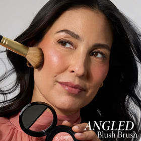 LAURA GELLER Angled Blush Brush on a vanity with makeup products