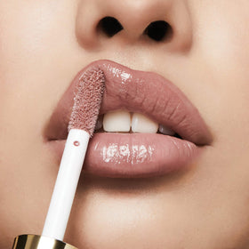 Milani lip gloss on a vanity with makeup tools