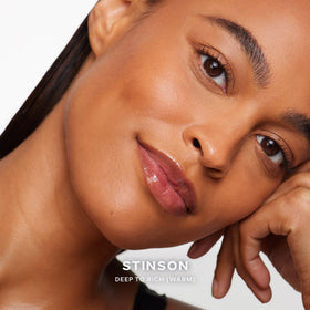 Model applying Saie Dew Bronze Liquid Bronzer on cheeks