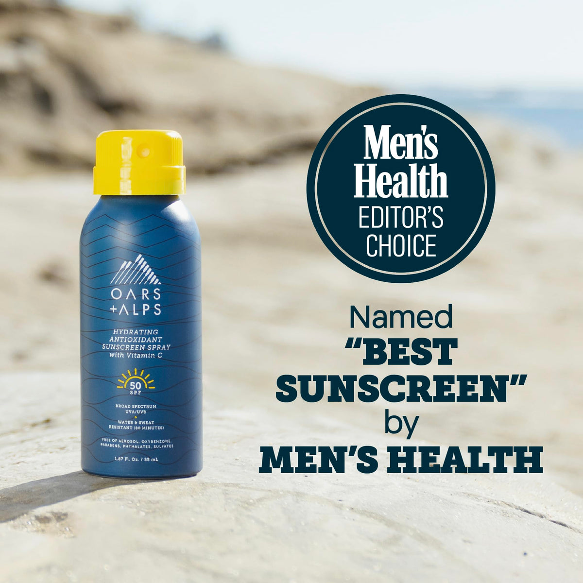 Oars + Alps SPF 50 Sunscreen Spray bottle side view on a beach