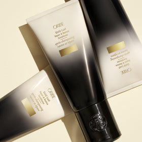 ORIBE Gold Lust Conditioner on a vanity with flowers