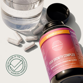 Primal Harvest Hair Growth Complex with a glass of water