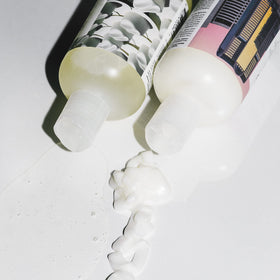 R+Co Dallas Biotin Thickening Shampoo and Conditioner set on a bathroom counter
