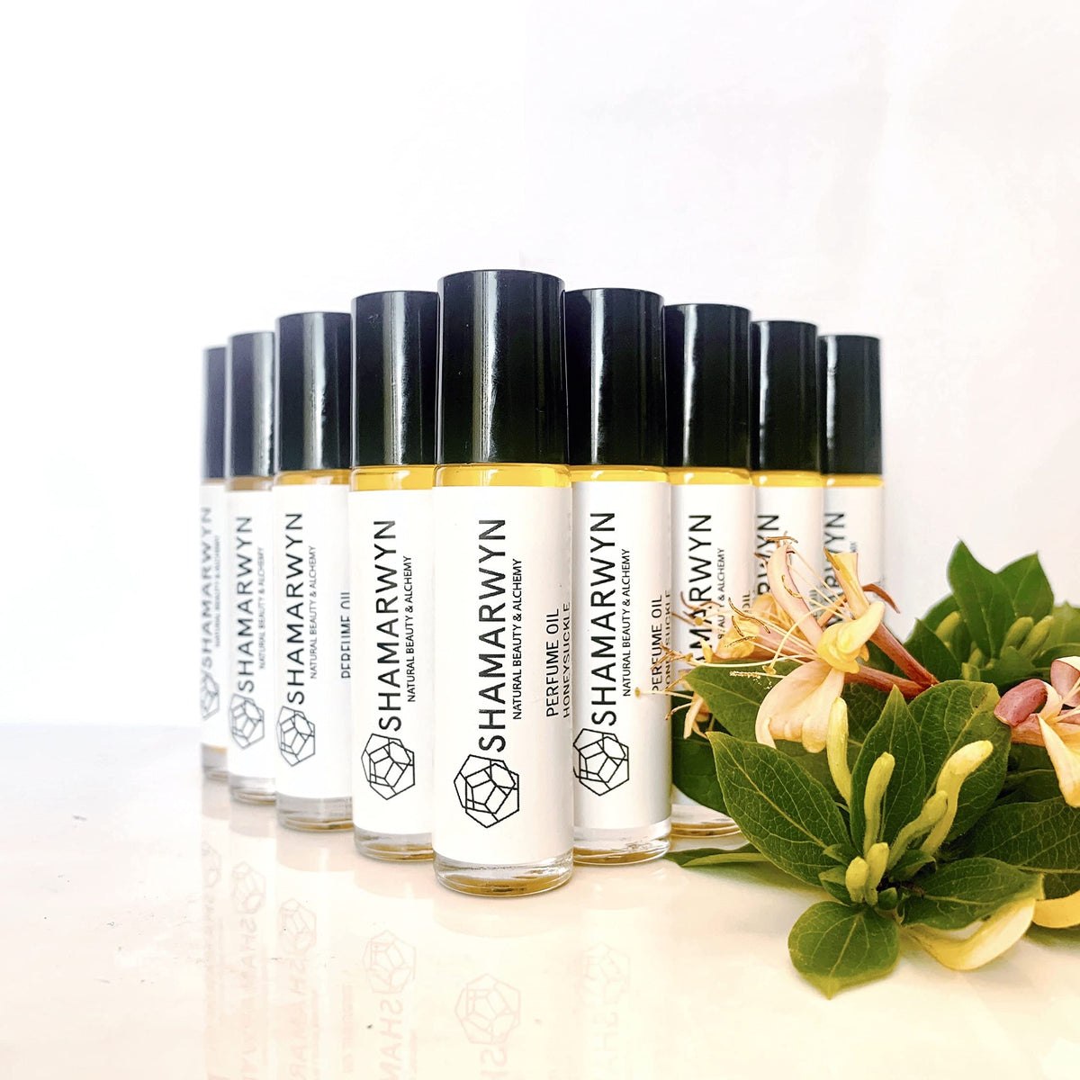 shamarwyn Honeysuckle Perfume Oil roll-on beside blooming honeysuckle flowers
