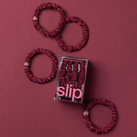SLIP skinny scrunchies in maroon displayed on a soft surface