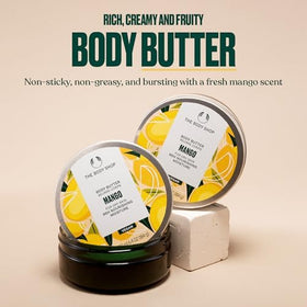 The Body Shop Mango Body Butter surrounded by fresh mango slices