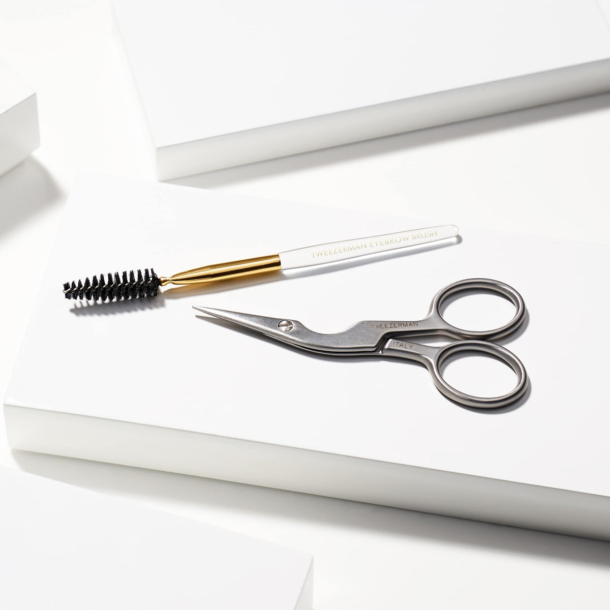 Tweezerman Eyebrow Shaping Scissors next to brow grooming tools