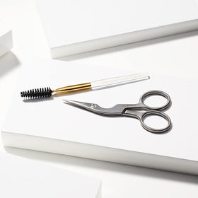Tweezerman Eyebrow Shaping Scissors next to brow grooming tools