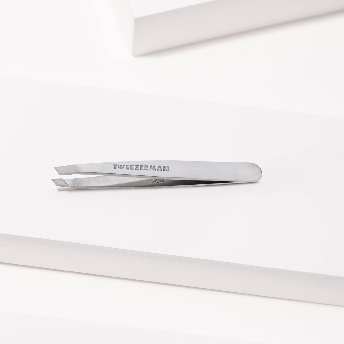 Tweezerman Mini Slant Tweezer held in hand for demonstration