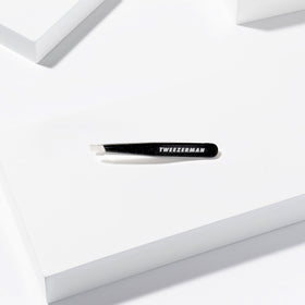 Tweezerman Mini Slant Tweezer on a bathroom counter