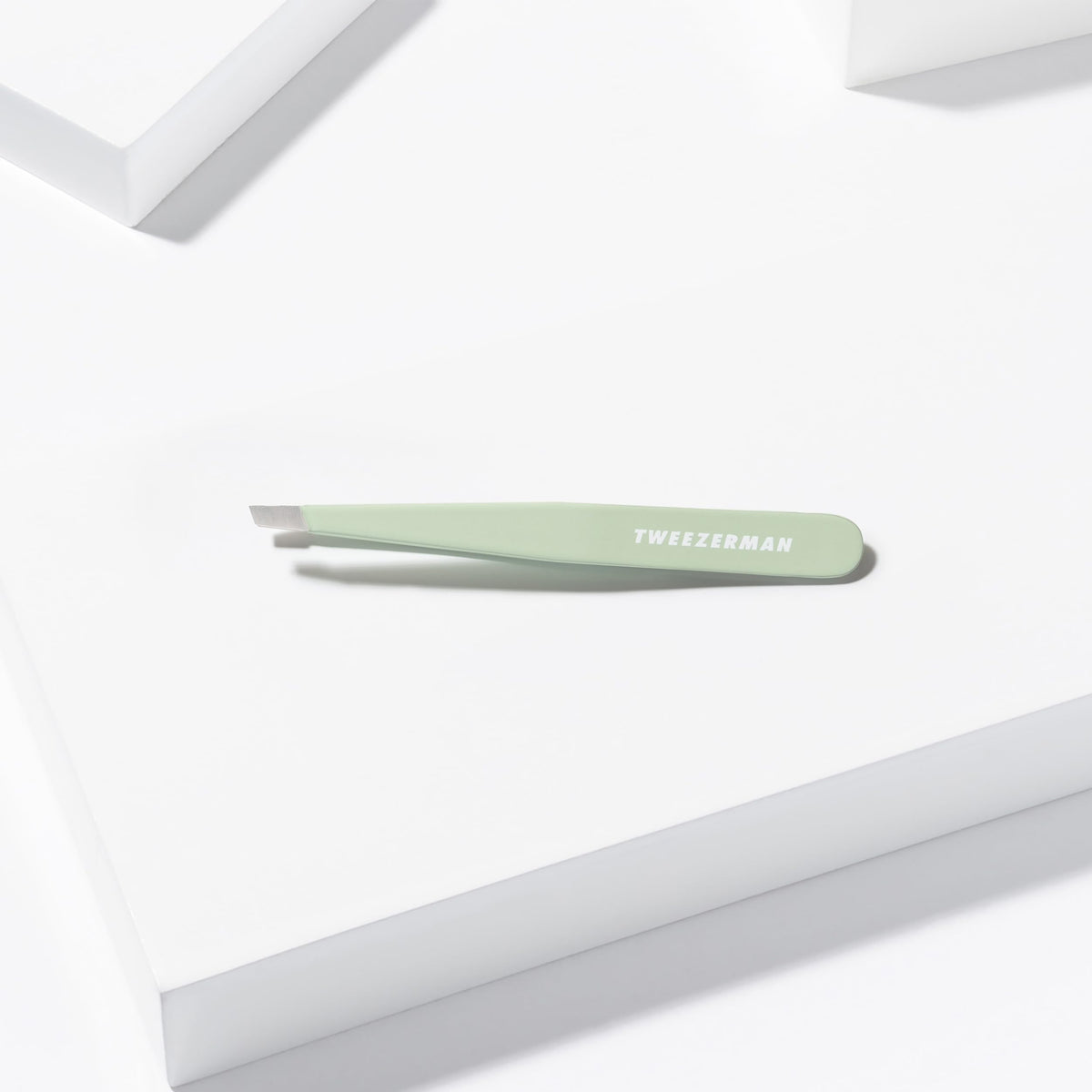 Tweezerman Slant Tweezer Pistachio next to beauty products