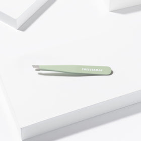 Tweezerman Slant Tweezer Pistachio next to beauty products